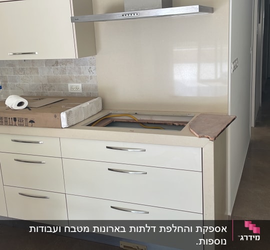 מטבח עם ארונות לבנים, כיור וברז, קופסה על השיש